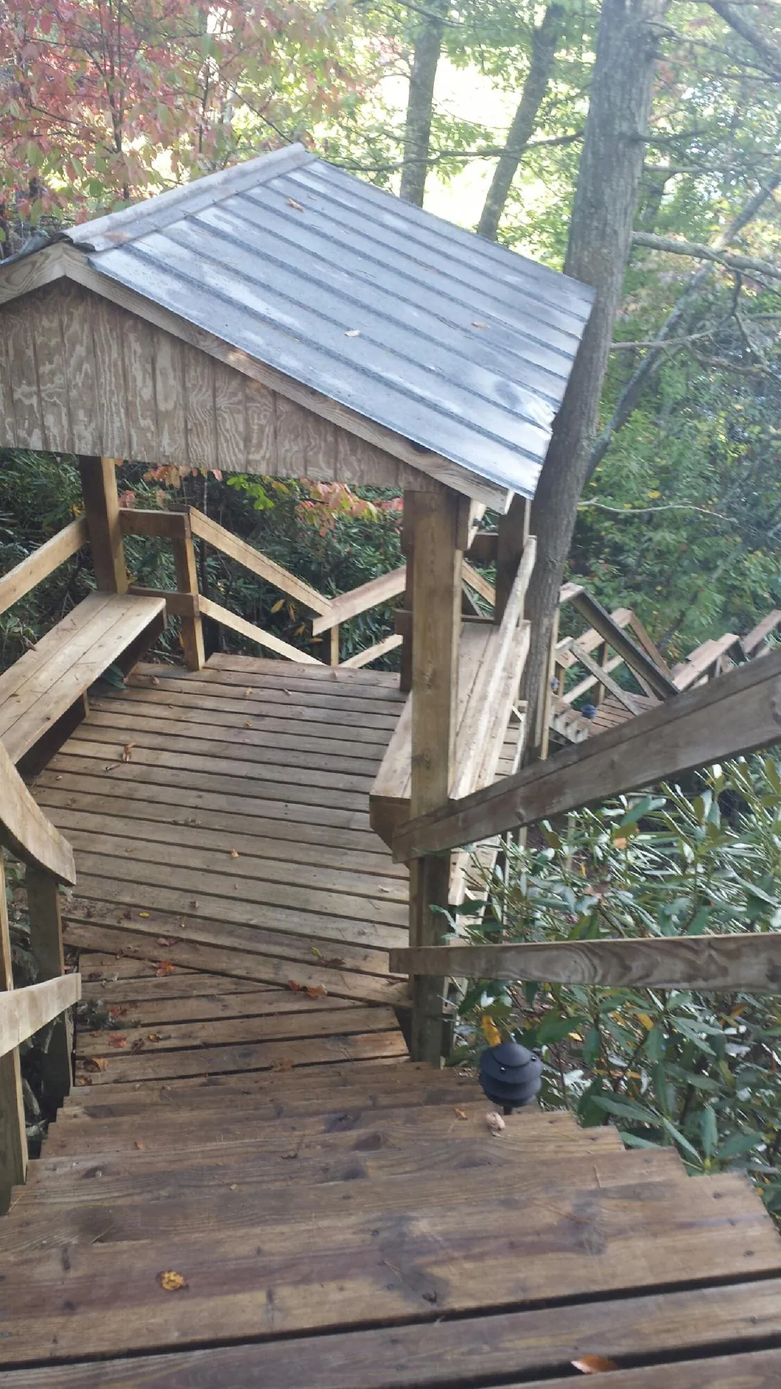 Metal roofed shelter over wooden steps on a wooded walkway — Skylight Repair & Installation work by our crew in Burlington